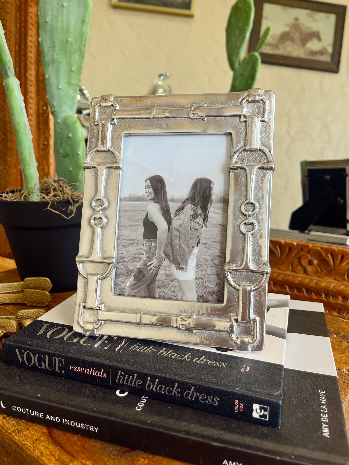 Decorative silver picture frame with a photo of two people on top of a Vogue book.
