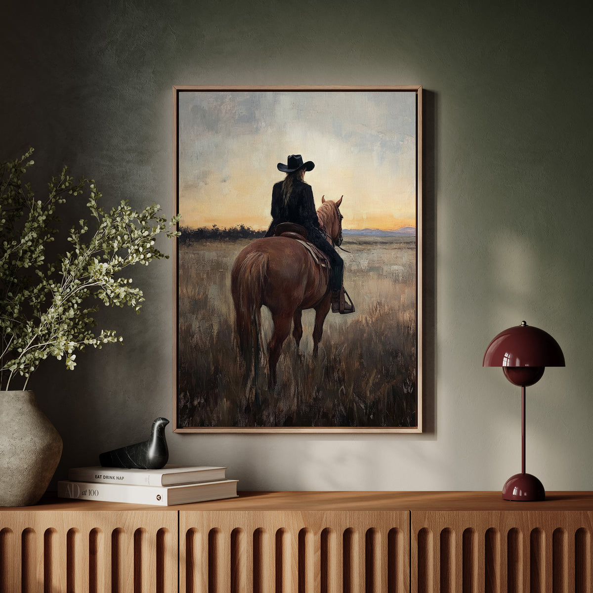 Framed painting of a person on horseback in a field, displayed on a wall above a wooden console table.