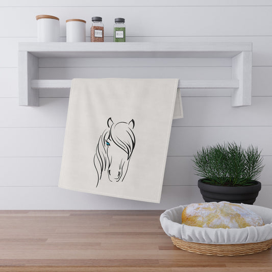 Kitchen towel with horse design hanging on a wooden shelf with a plant and basket below.