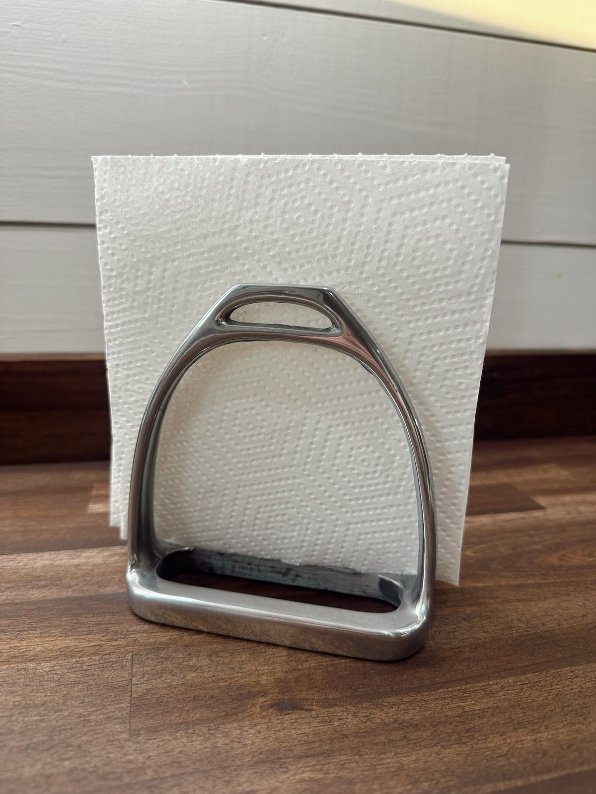 Metal stirrup on a wooden surface with a white textured background