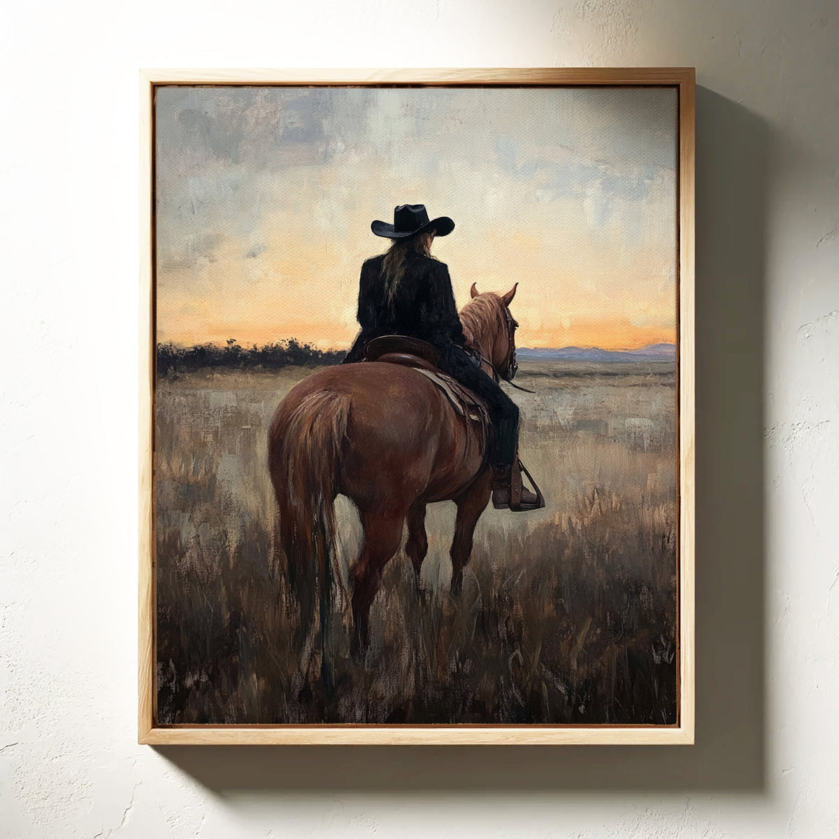 Framed painting of a person on horseback against a sunset sky.