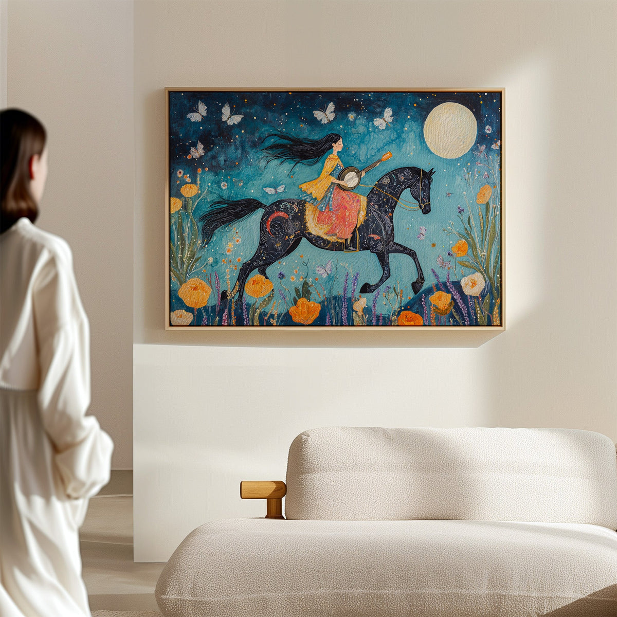 Woman looking at a colorful painting of a person riding a horse on a wall in a room with a white sofa.