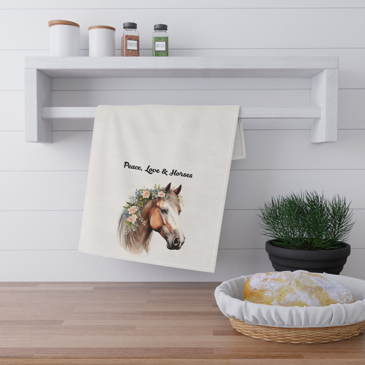 Towel with horse design and text hanging on a rack in a kitchen setting.