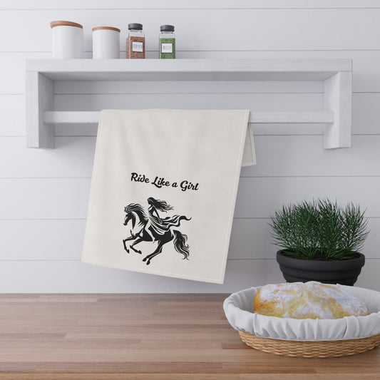 Kitchen towel with horse graphic and text hanging on a rack, with a plant and basket in the foreground.
