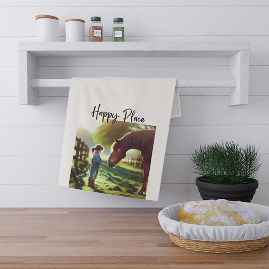 Towel with a horse and person design hanging on a wooden shelf with a plant and basket below.