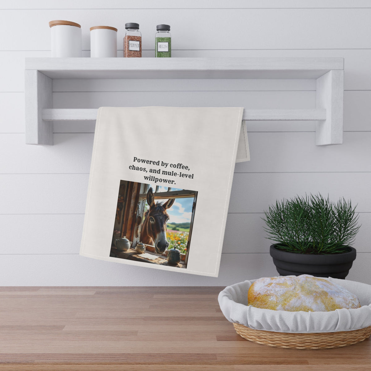 Towel with a donkey image and text on a kitchen counter with a plant and basket.