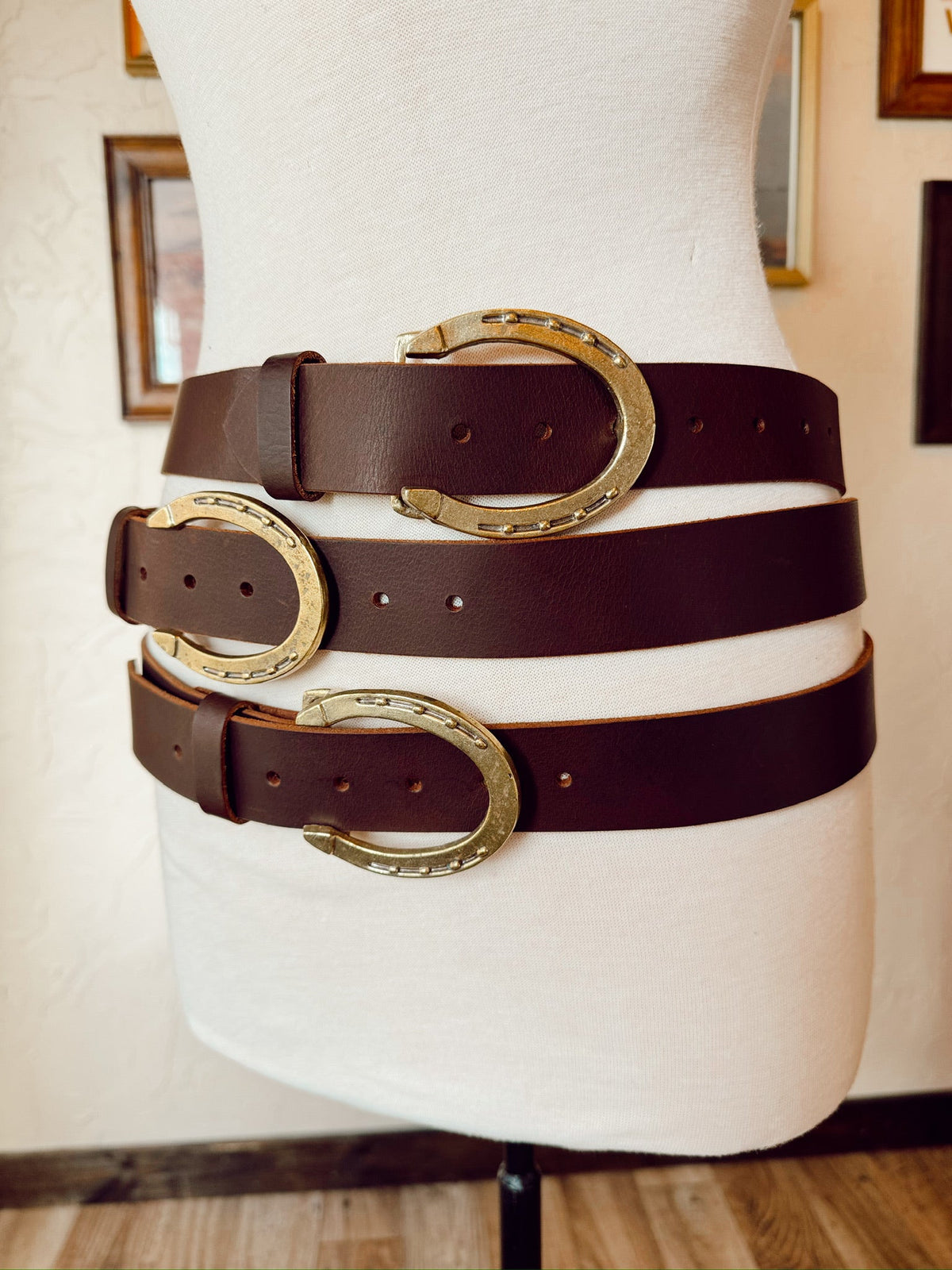 Mannequin wearing a brown belt with gold buckles against a neutral background