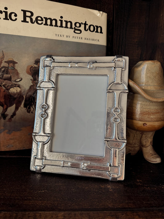 Decorative picture frame with a cowboy theme in front of a book titled 'Ned Buntline's Life of Buffalo Bill' and a cowboy hat.