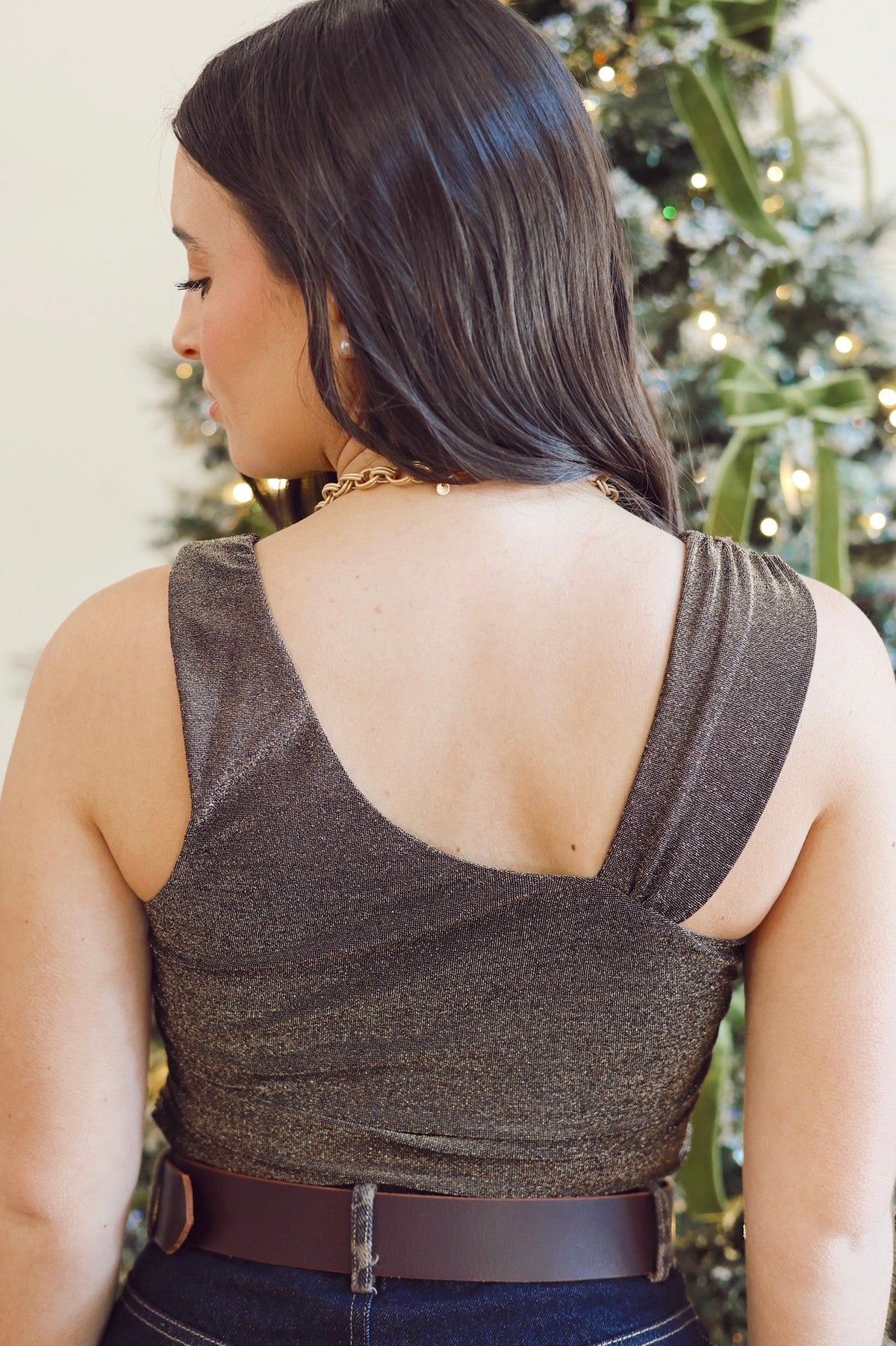 Woman wearing a sparkly brown top with a Christmas tree in the background