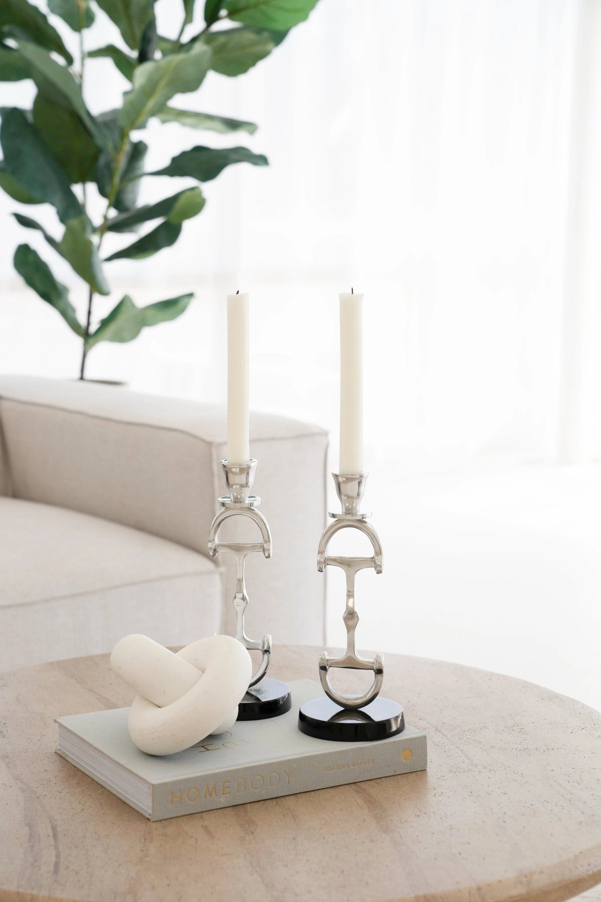 Decorative items on a table with candles and a plant in the background