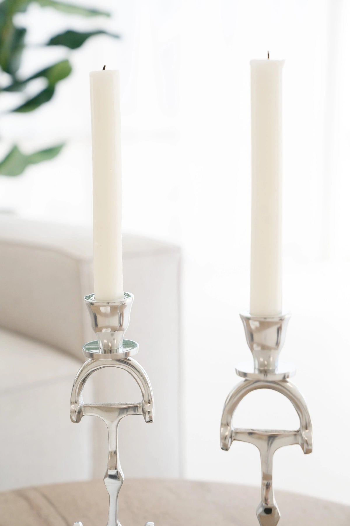Two silver candle holders with white candles on a neutral background