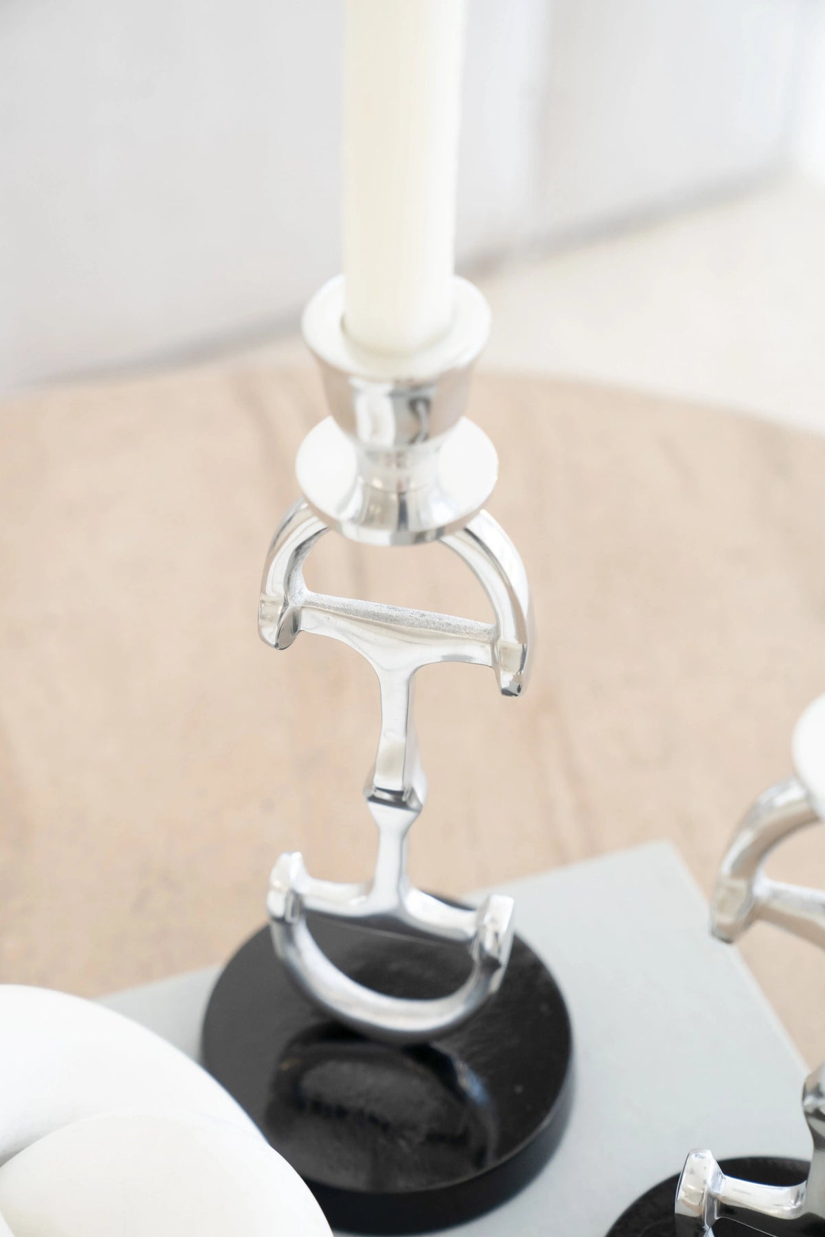 Decorative candle holder with black base and silver metalwork on a neutral background