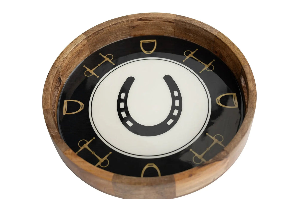 A round wooden serving tray with a black and white horseshoe design and gold-colored equestrian symbols, isolated on a white background.