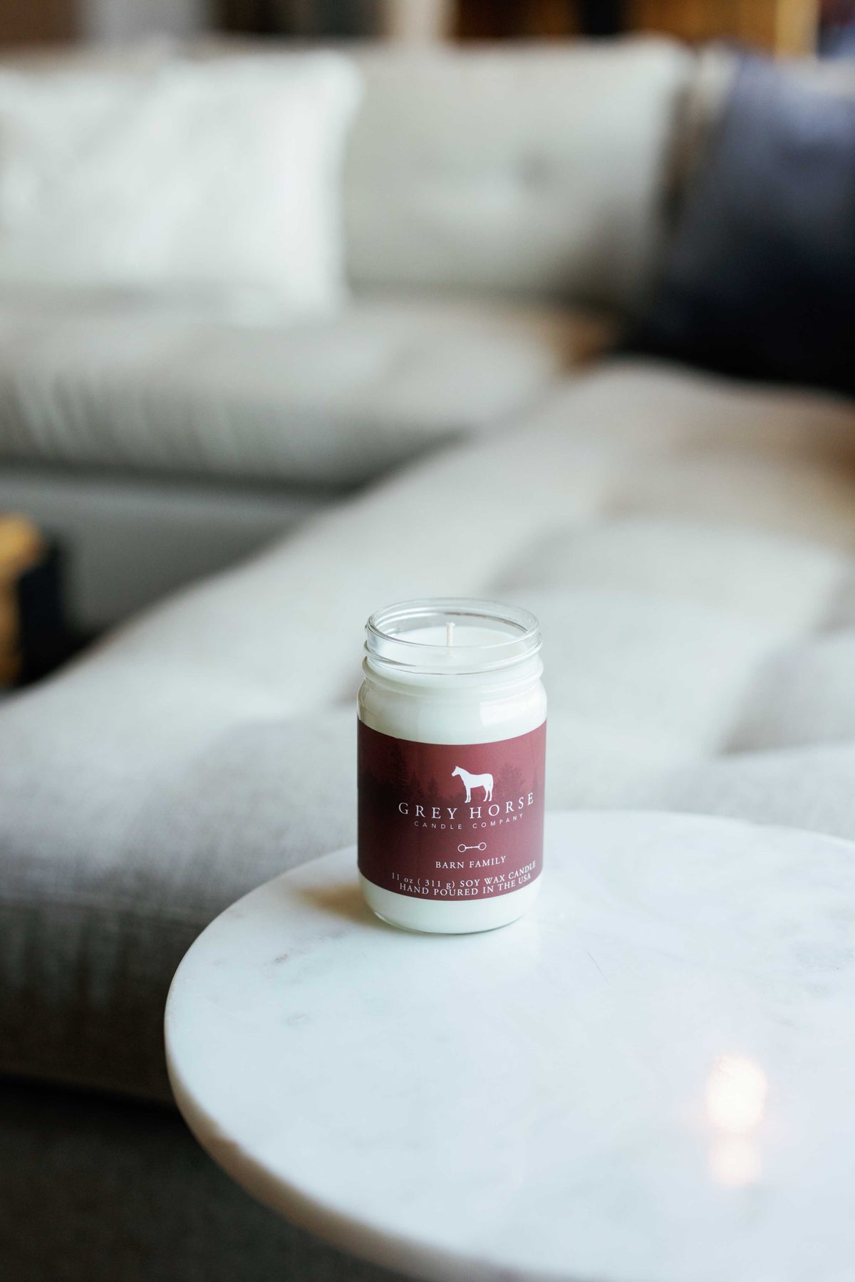 Jar of Grey Horse Soap Company on a marble surface with a blurred sofa in the background