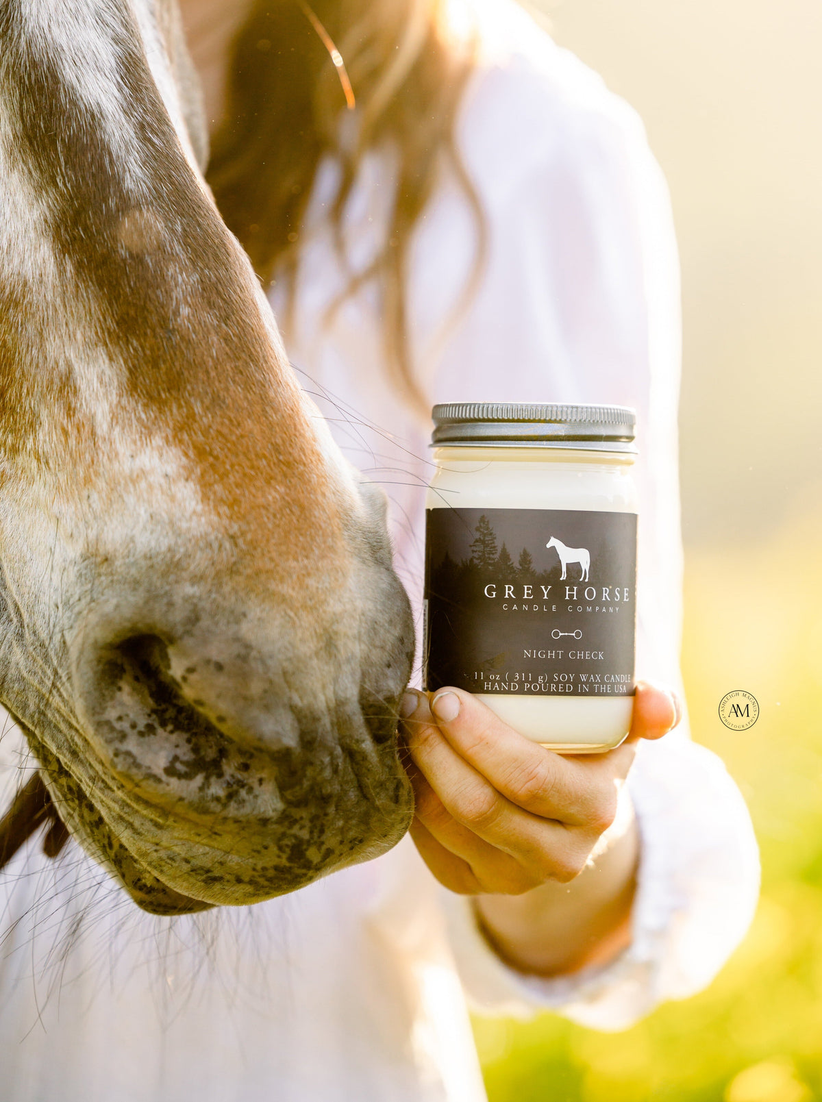 Person holding a jar labeled 'Grey Horse' next to a horse in a field