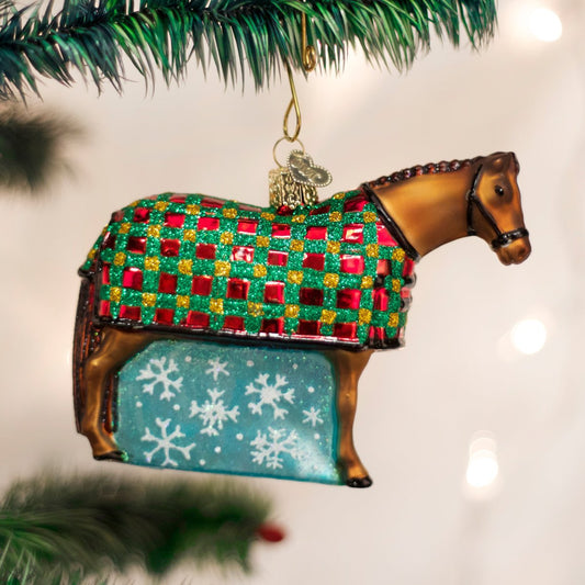 Horse-shaped Christmas ornament with a checkered blanket and snowflake pattern, hanging on a tree.