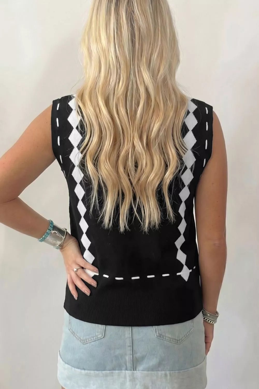 Person wearing a black sleeveless top with white geometric patterns on a plain background
