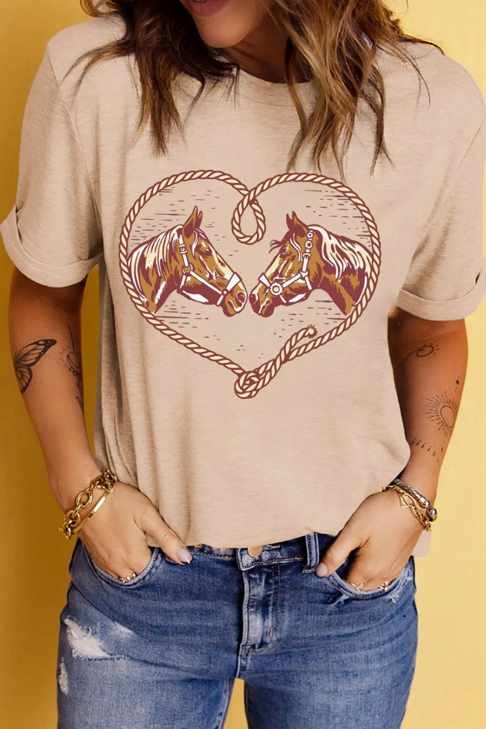 Person wearing a beige t-shirt with horse design on a yellow background