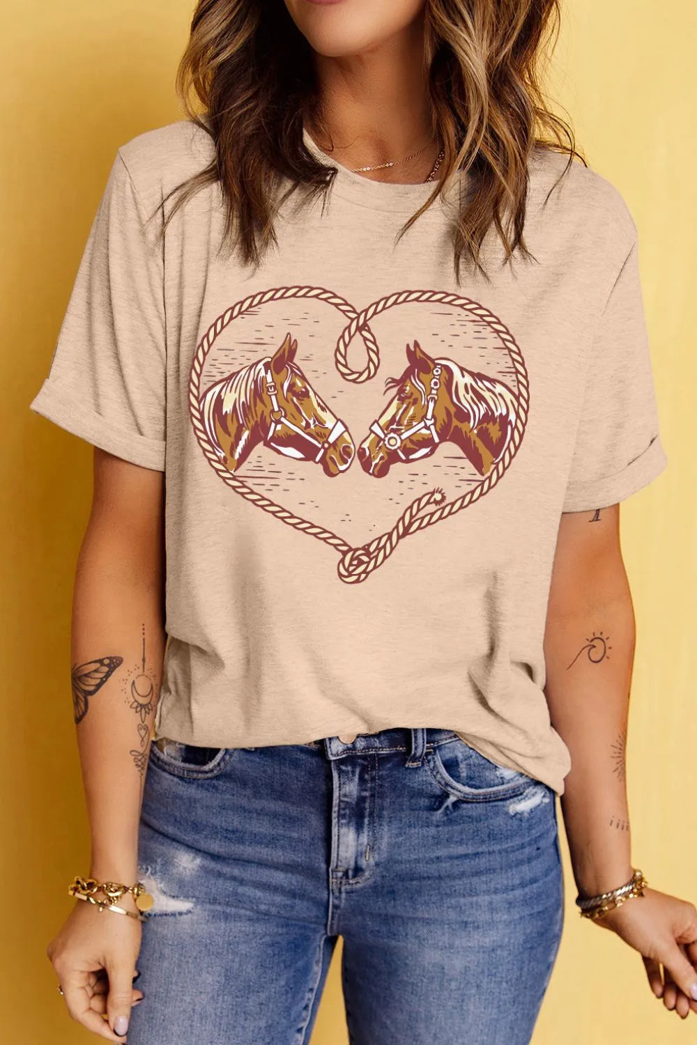 Person wearing a beige t-shirt with horse design on a yellow background