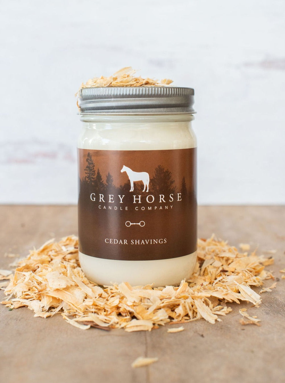 Jar of candle from Grey Horse Candle Company with cedar shavings on a wooden surface