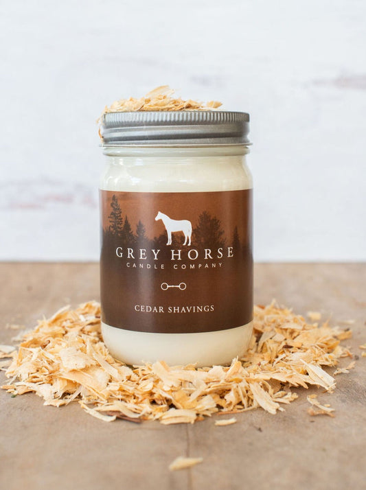 Jar of candle from Grey Horse Candle Company with cedar shavings on a wooden surface