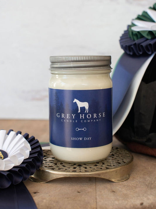 Candle jar with 'Grey Horse Candle Company' label on a wooden surface with decorative items.