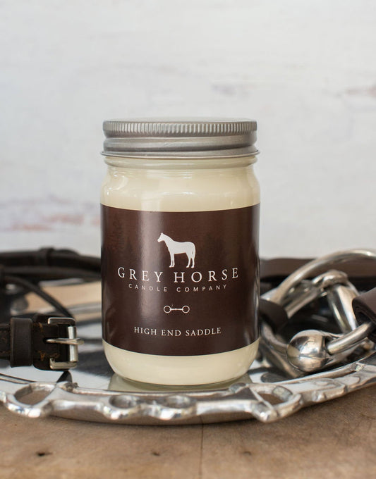 Jar of candle from Grey Horse Candle Company on a rustic background with horse equipment.